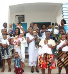 A group of people standing outside holding baby 's.